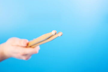 Close up male hands holding drumsticks on an isolated blue background. Concept of drumming lessons, online courses and learning at home. Favourite hobby. Background with copy space