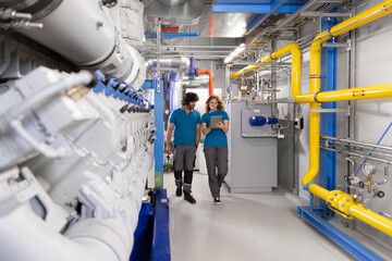 Technician colleagues discussing over tablet PC to colleague in factory