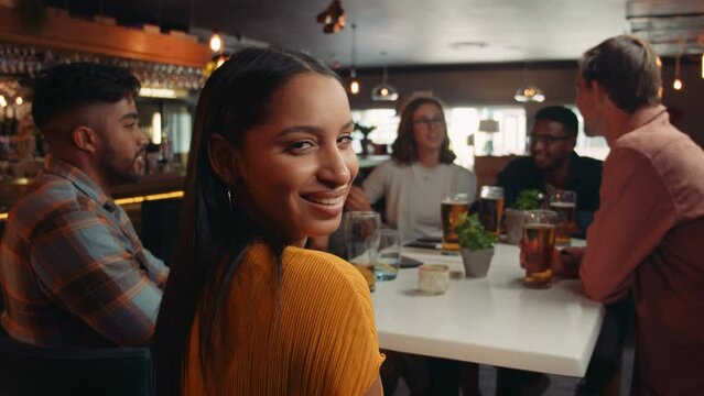 Beautiful woman smiling at camera with diverse group of friends out for dinner