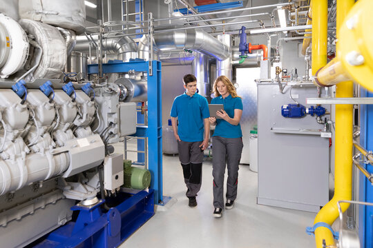 Technician showing tablet PC to trainee in factory