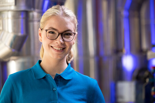 Smiling technician wearing eyeglasses standing in factory