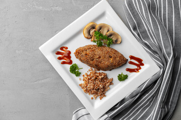 Cutlet with buckwheat with mushrooms on square plate