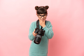 Little photographer girl isolated on pink background thinking