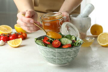 Woman adds honey mustard sauce to salad
