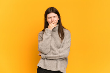 Young Ukrainian girl isolated on yellow background having doubts and with confuse face expression