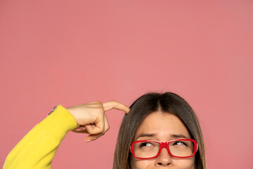 half portrait of a young woman with eyeglasses scratching her head