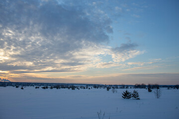 Winter minimalist landscape with colorful clouds in the sky and smoking chimneys on the horizon. winter tourism