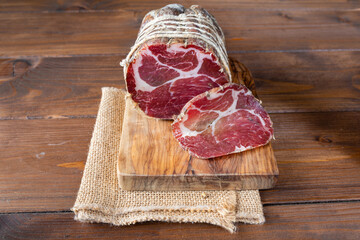 Capocollo of martina franca on wooden table typical from apulia south italy. Italian salami