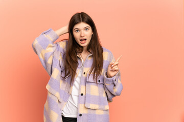 Young Ukrainian girl isolated on pink background surprised and pointing finger to the side