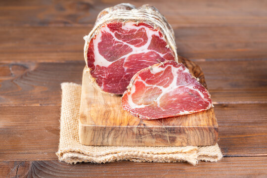 Capocollo of martina franca on wooden table typical from apulia south italy. Italian salami