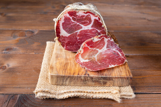 Capocollo of martina franca on wooden table typical from apulia south italy. Italian salami