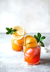 Refreshing alcohol juice cocktail decorated with green leaf. Food photo drink beverage with ice cubes, juice