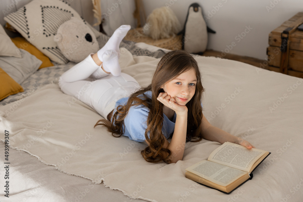 Wall mural portrait of a beautiful cute girl in bed with a book	