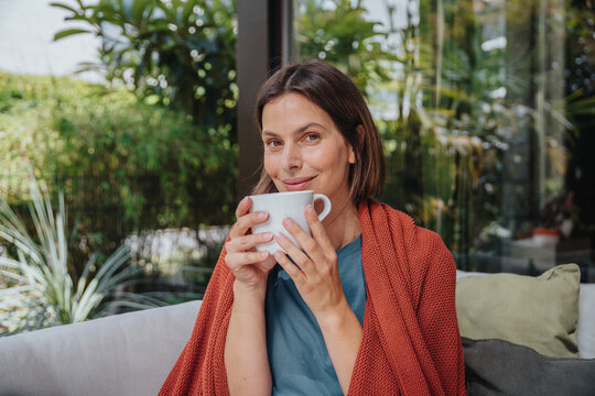 Smiling woman with coffee cup at back yard