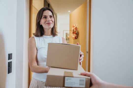 Smiling woman receiving packages from delivery person at door