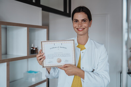 Smiling doctor showing certificate in clinic
