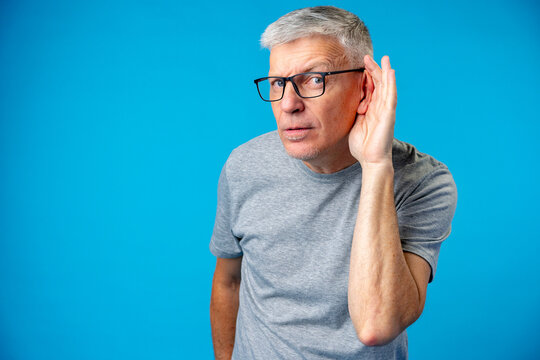 Middle age man over iblue background with hand over ear listening