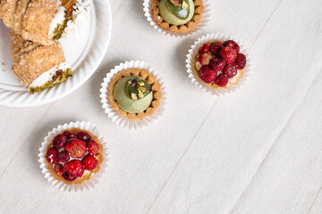 Delicious tartlets dessert assorted pastries. Mini tartlets with cream cheese, pistachio cream filling and strawberries. Closeup of delicious pastry sweets pies.