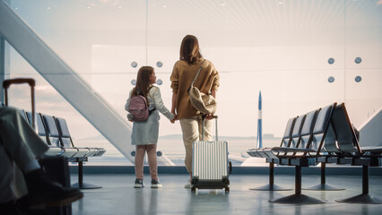 Airport Terminal: Beautiful Mother and Cute Little Daughter Wait for their Vacation Flight, Looking...