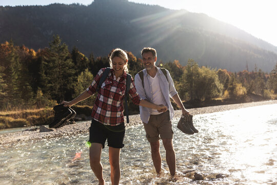 Austria, Alps, couple on a hiking trip wading in a brook