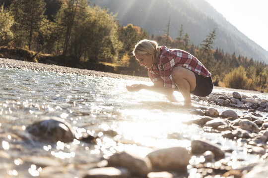 Austria, Alps, woman on a hiking trip having a break at a brook