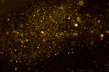 Fototapeta na wymiar Abstract background of sparkling shiny golden glitter particles bokeh on black