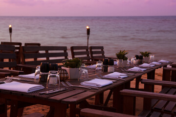 Outdoor restaurant table dinner setting on beach at sunset