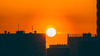 Zonsopgang in de stad. Close-up van de gele zon die opkomt boven woongebouwen.