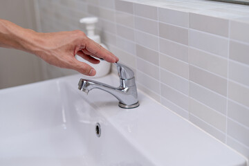 The faucet in the bathroom with running water. Man keeps turning off the water to save water energy...