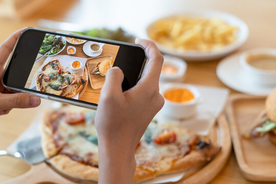 italian food. The restaurant owner takes a picture of the food on the table with a smartphone to post on a website. Online food delivery and ordering service