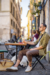 Man sitting with a dog at restaurant on the street in Rome. Concept of italian lifestyle. Idea of...