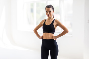 Fototapeta na wymiar Portrait of beautiful fitness woman smiling and looking at camera isolated on grey background. Young woman in sportswear relaxing after training at gym.
