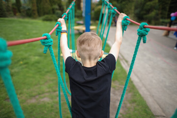 view from the back as a boy passes an obstacle course, engages in active sports, walks on a cable car