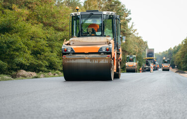Vibratory asphalt rollers compactor compacting new asphalt pavement. Road service repairs the highway