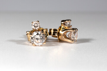 Yellow gold earrings with natural round diamonds on a white background