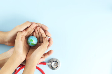World health day concept - hands hold blue earth on blue background with stethoscope