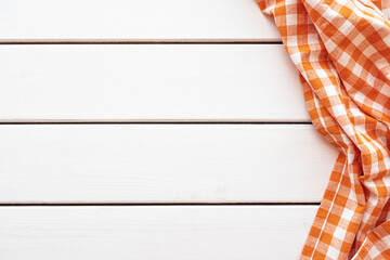 Checked orange tablecloth on white wooden background