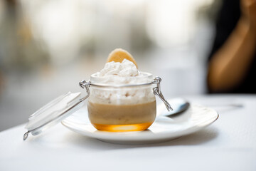 Tiramisu dessert in glass jar at restaurant table. Classic Italian dessert serving