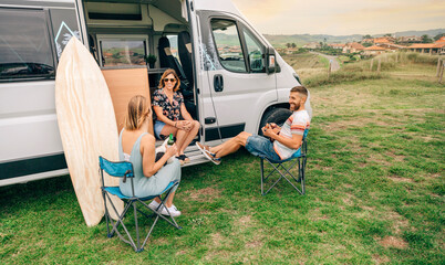 Group of friends with their dog talking and drinking beer in front of their camper van © David Pereiras