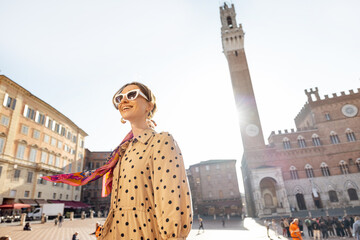 Portrait of a woman on background of town hall of Siena city, traveling famous places in Tuscany. Concept of visiting italian landmarks and style - obrazy, fototapety, plakaty