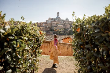 Papier Peint photo Toscane Stylish woman walks on background of cityscape of Siena old town. Concept of travel famous cities in Tosacny region of Italy