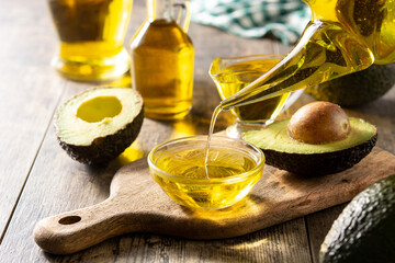 Oil and ripe fresh avocado on rustic wooden table - obrazy, fototapety, plakaty
