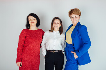 Studio shot of three women on a white background. Shooting in business style. Three girlfriends in the office