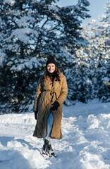 Fototapeta na wymiar Smiling woman walks in forest in sunny winter day.