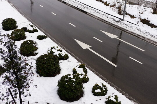 Winter road with two parallel white arrows. White arrows on a wet asphalt road.