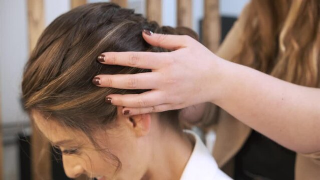 Professional stylist doing a wedding headdress to her female client at the beauty salon.