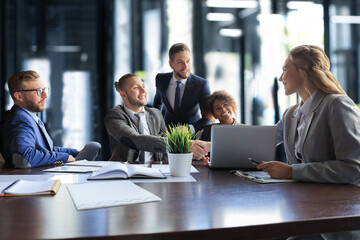 Young modern businessmen in formalwear shaking hands and smiling while working in the office