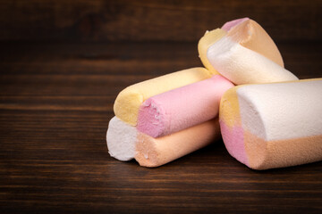 Sweets, colored marshmallows on a dark wooden background