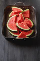 Watermelon cut into slices. Dark wood background. Autumn photos.