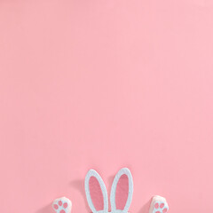 Cute fluffy white pink bunny ears and paws on a pastel pink background. Text space. Top view. Minimal style.